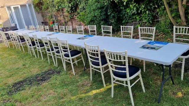 Long outdoor tables with white Chiavari chairs in a garden