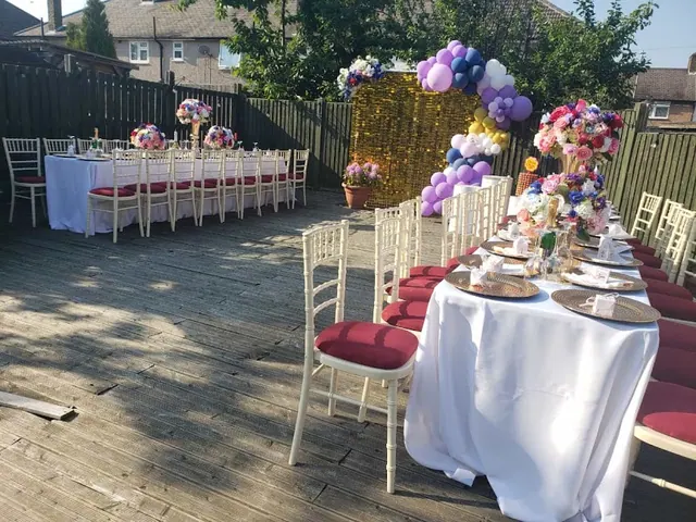Garden celebration tables with floral arrangements and a purple balloon backdrop