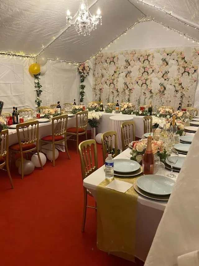 A lined dining marquee with chandeliers, red carpet and a floral backdrop