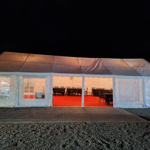 Illuminated marquee at night with an open front and covered tables and chairs inside