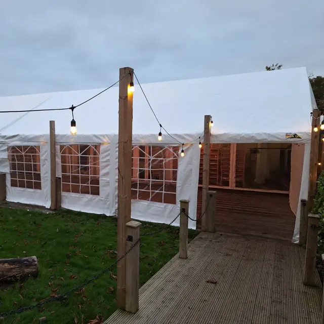 White marquee beside timber decking with festoon lights