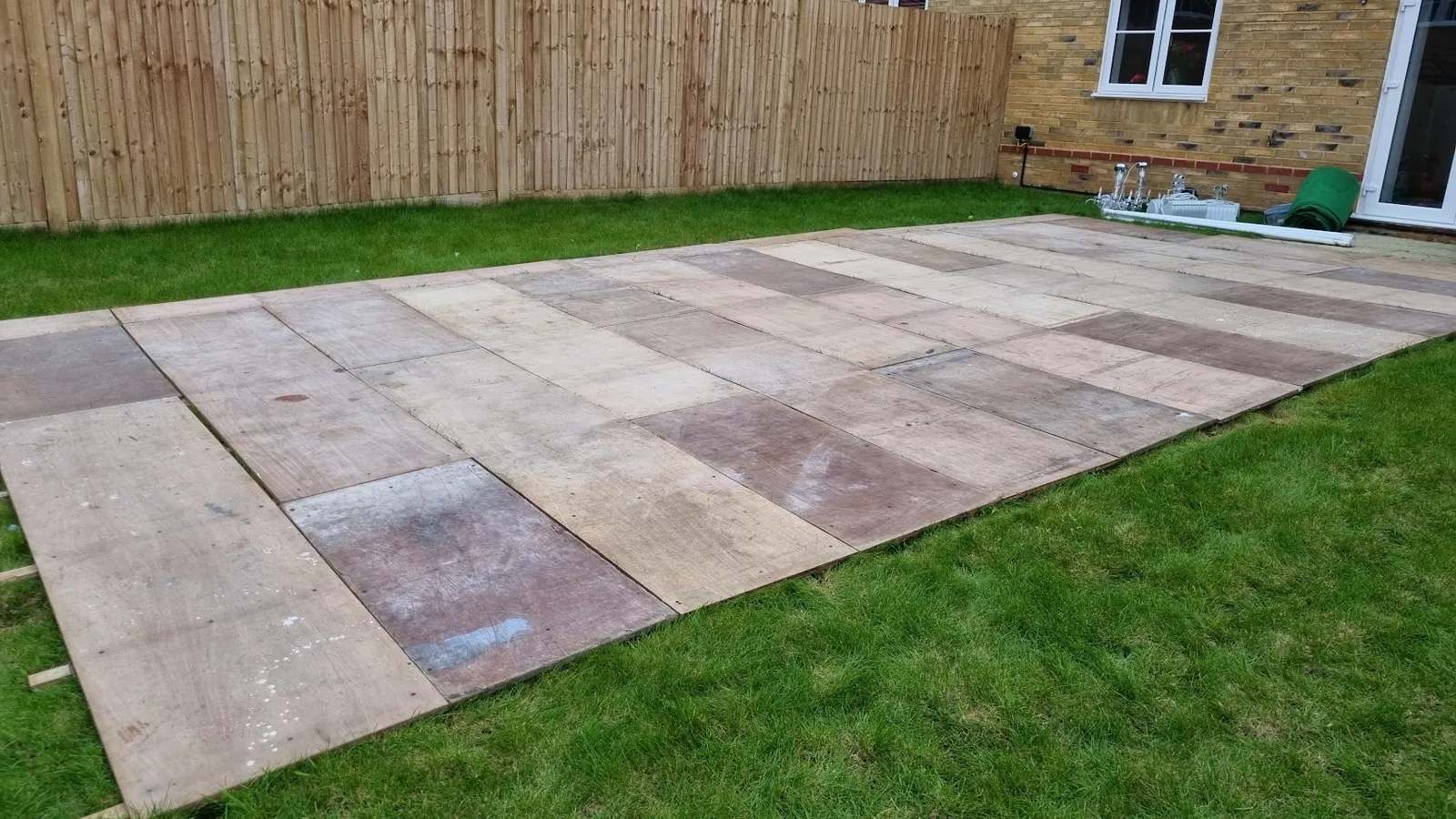Hard flooring panels laid across a garden lawn