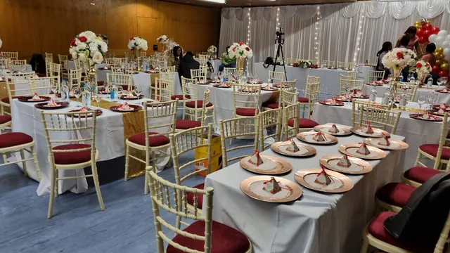 Long dressed tables with gold Chiavari chairs and red seat pads