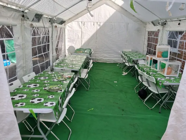 Green-covered tables set with football-themed plates inside an open-frame marquee